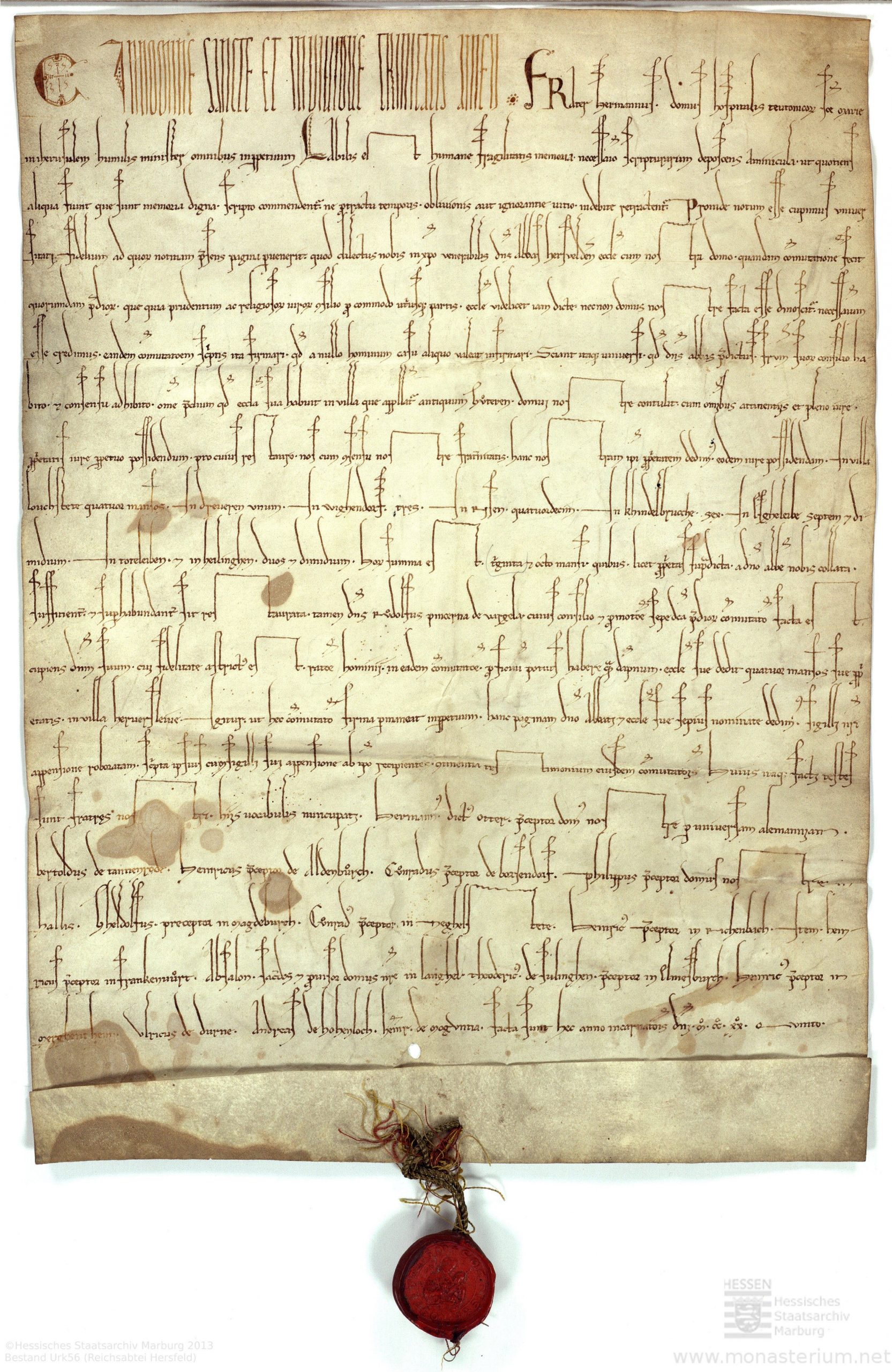 Das Bild zeigt eine Urkunde an der unten mit einem Band ein auf roten Wachs gedrucktes Siegel angbracht ist.
