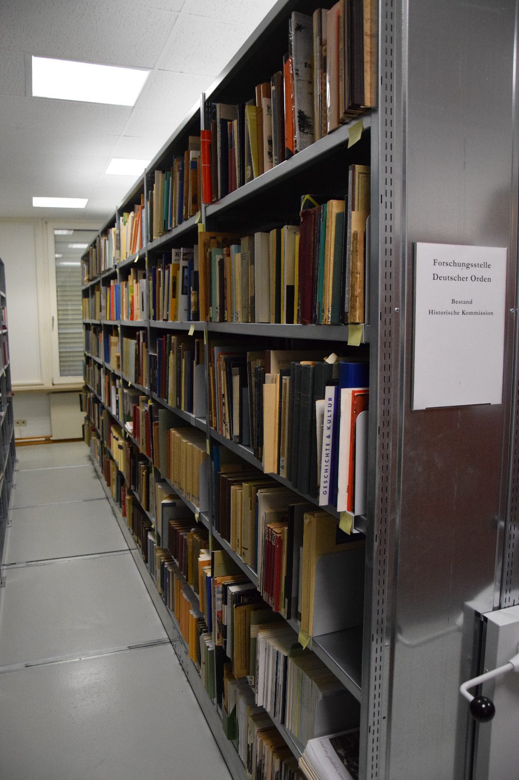 Das Bild zeigt ein Rollregal mit Büchern in der Bibliothek der Forschungsstelle des Deutschen Ordens.