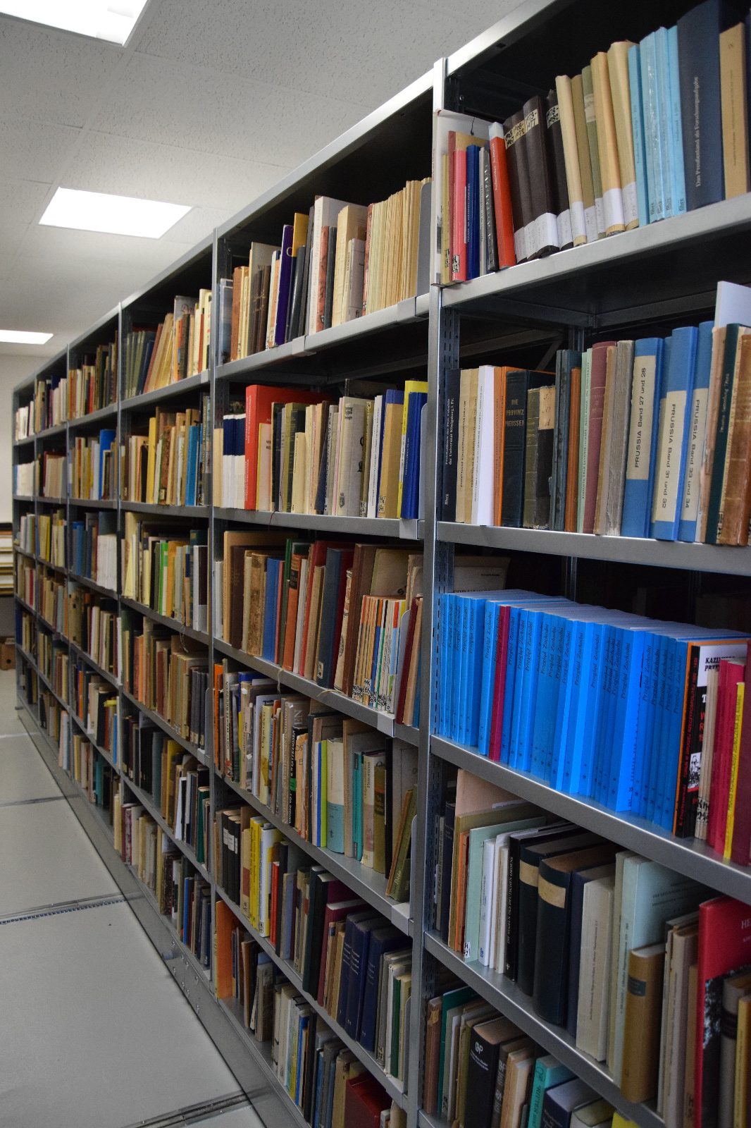 Das Bild zeigt ein Regal mit Büchern in der Bibliothek der Forschungsstelle des Deutschen Ordens.