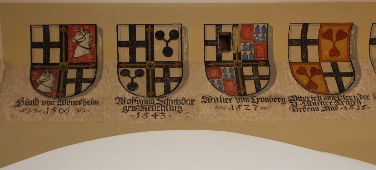 Das Bild zeigt eine Wappengalerie mit vier Wappen der Deutschmeister: Hund von Wenckheim, Wolfgang Schutzbar, Walter von Cronberg und Dietrich von Cleen.