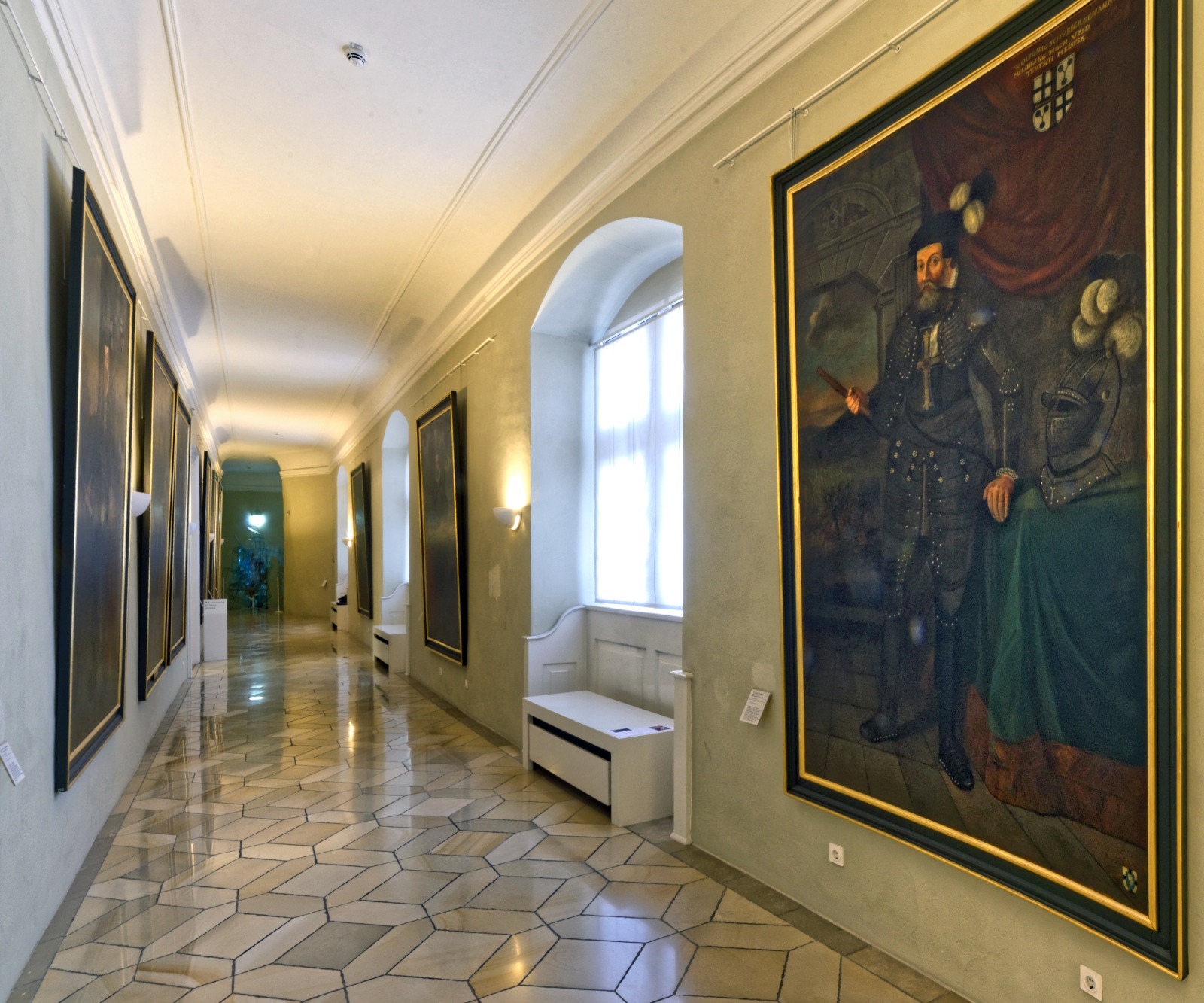 Das Bild zeigt die Hochmeistergalerie in Bad Mergentheim, die auf beiden Seiten mit großen Porträts der Hochmeister des Deutschen Ordens gesäumt ist.