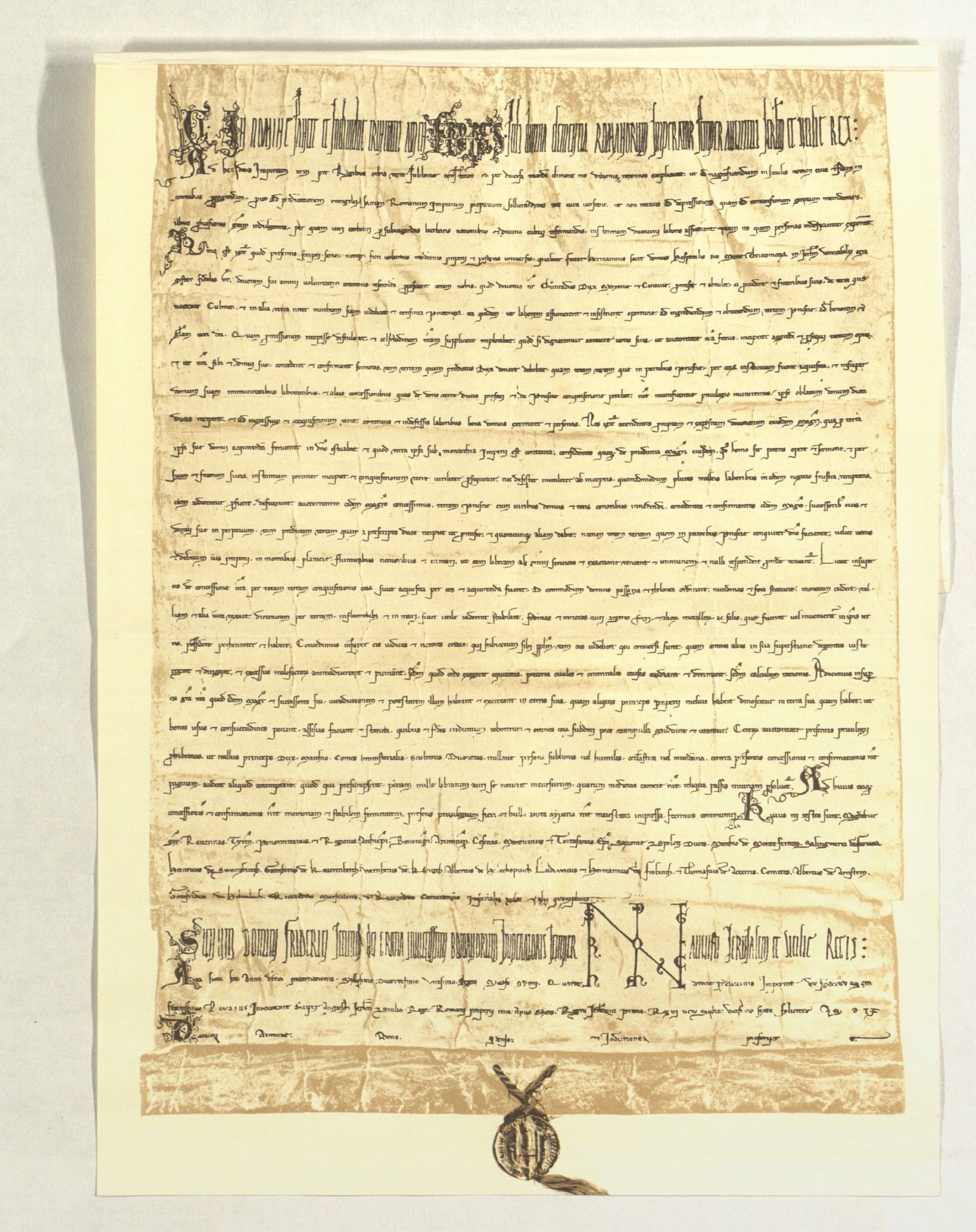 Das Bild zeigt die sogenannte "Goldbulle von Rimini", bei der es sich um eine Urkunde handelt. Am unteren Rand der Urkunde ist mit einem Faden ein Siegel befestigt.