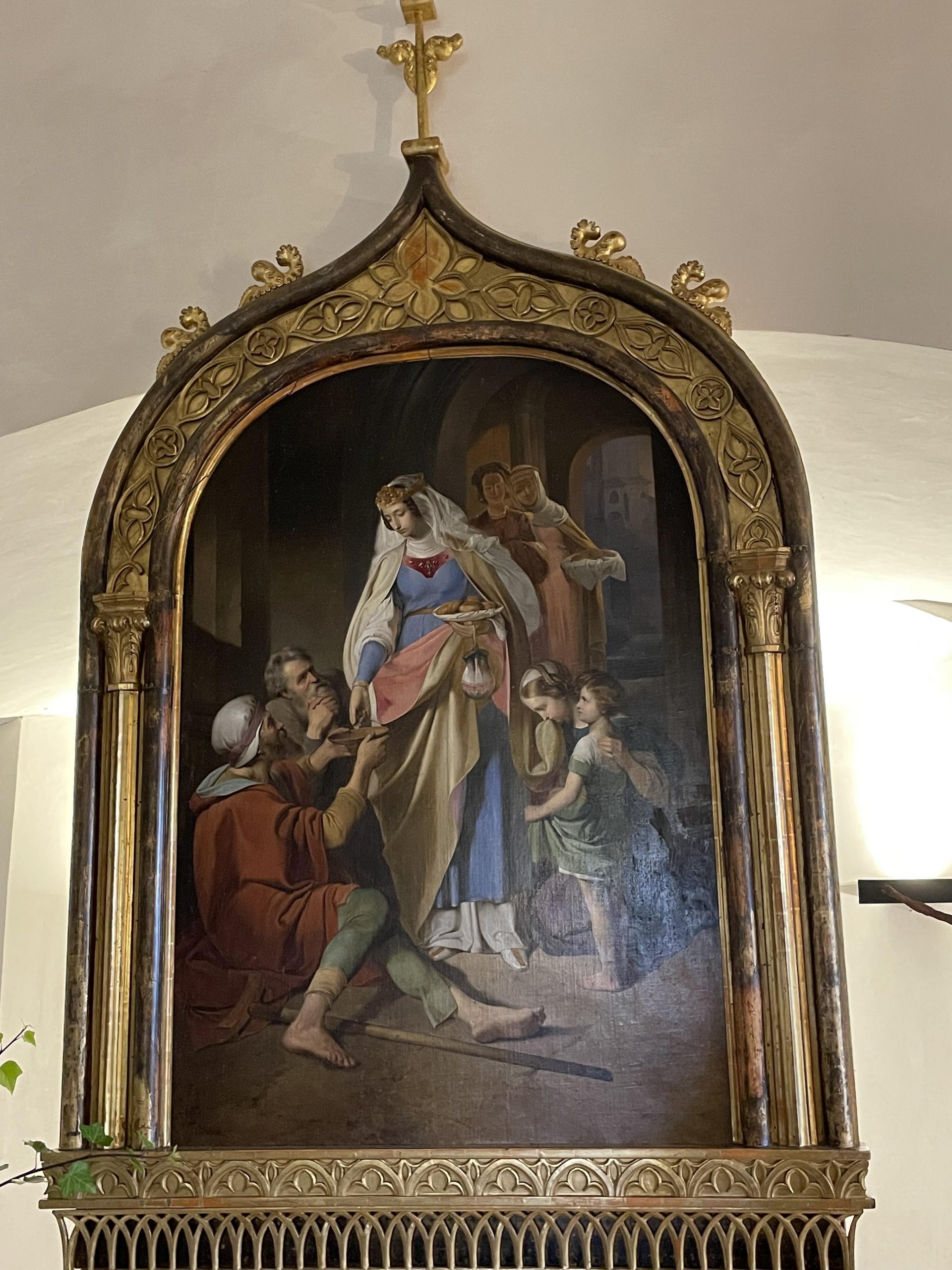 Das Bild zeigt ein Gemälde von Franz Eyb, auf dem die Heilige Elisabeth bei der Speisung von Bedürftigen dargestellt ist.